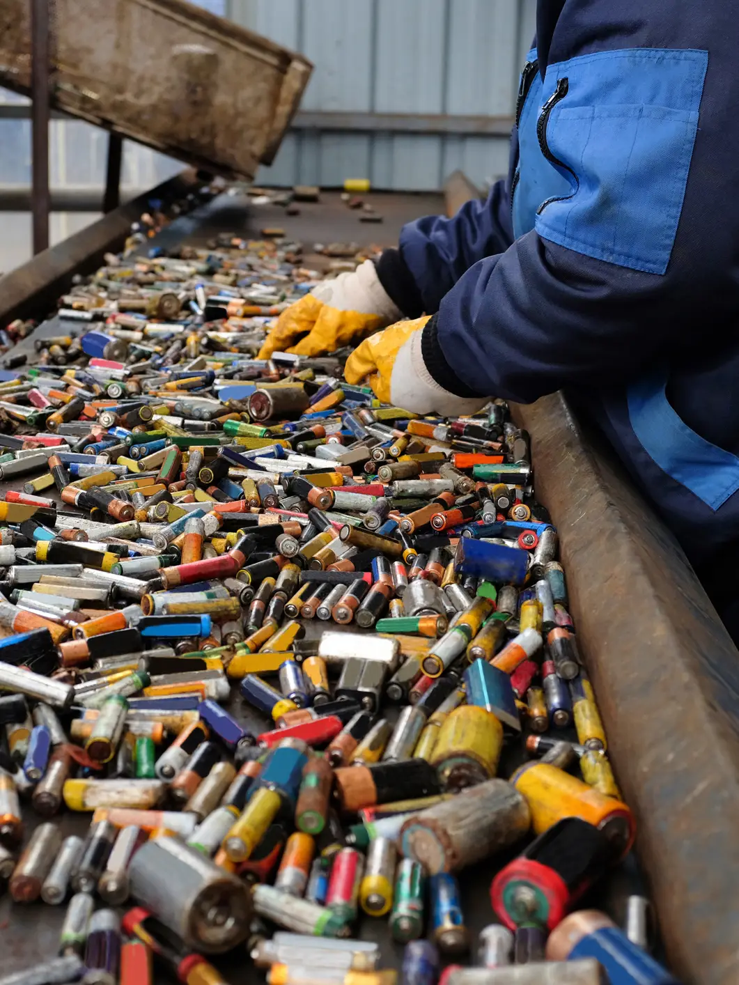 Worker sorting batteries at a recycling facility